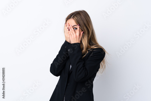 Young business woman over isolated white background covering eyes and looking through fingers