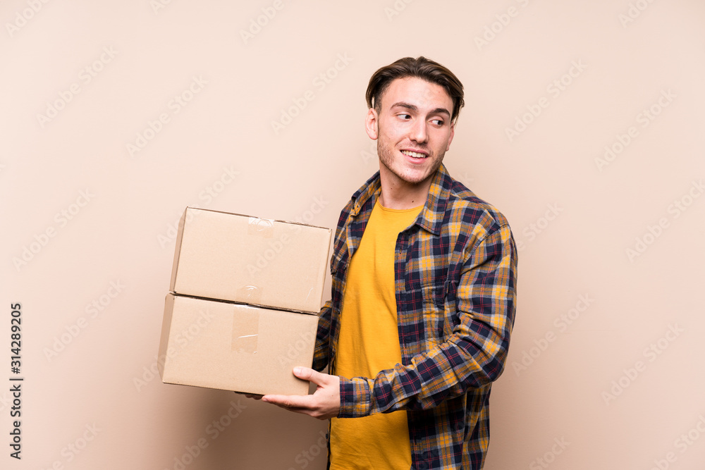 Young caucasian man holding boxes looks aside smiling, cheerful and pleasant. Young caucasian man holding boxes looks aside smiling, cheerful and pleasant.