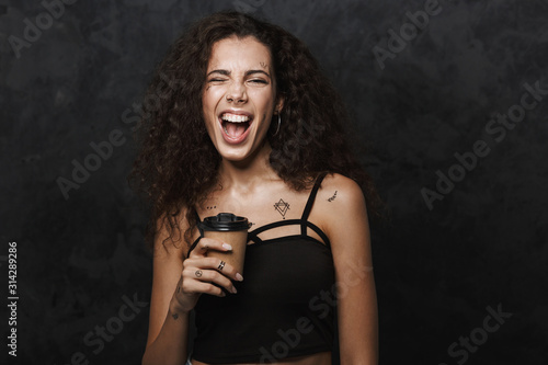 Image of nice cheerful woman winking and drinking coffee takeaway