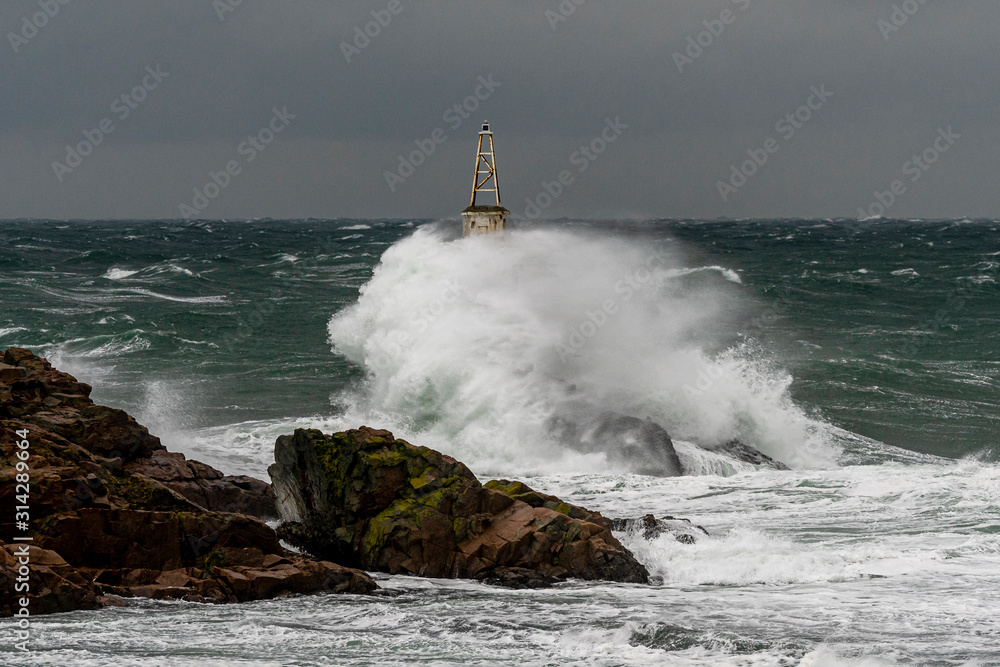 Dramatic seascape. Huge waves hit the lighthouse during severe sea storm. 