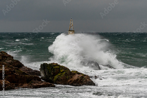 Dramatic seascape. Huge waves hit the lighthouse during severe sea storm. 