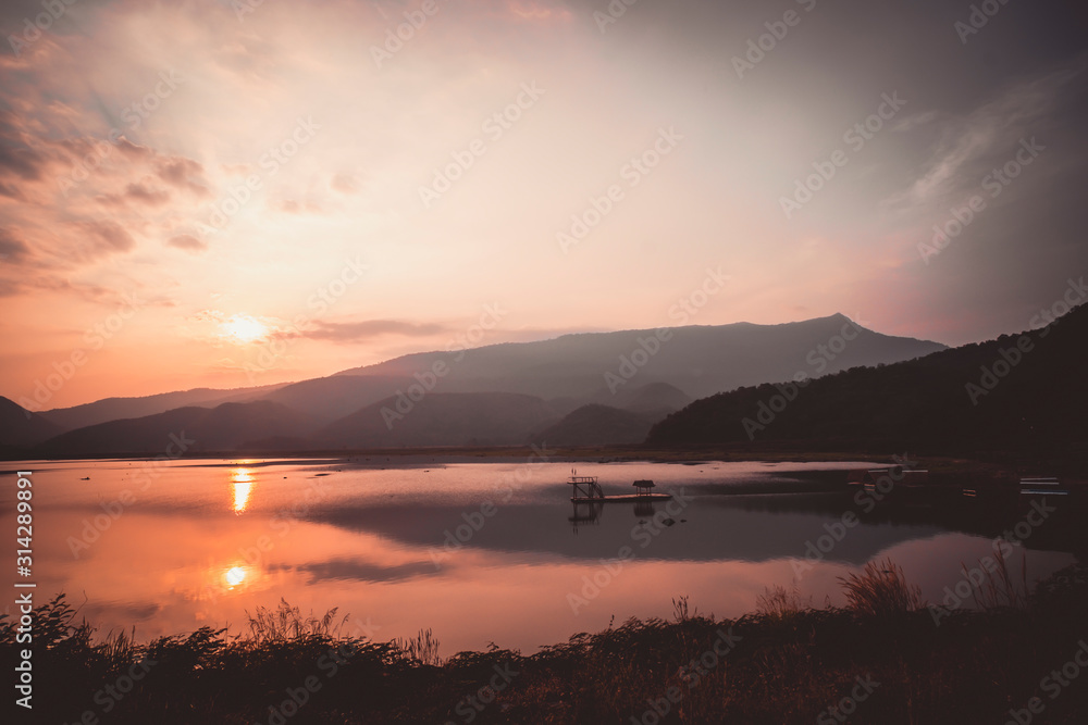 Dramatic  sunset landscape with orange sky.  silhouettes of mountains. sky of lake landscape at sunset .sky and hills reflect on  the background. 