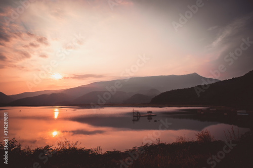 Dramatic sunset landscape with orange sky. silhouettes of mountains. sky of lake landscape at sunset .sky and hills reflect on the background. 