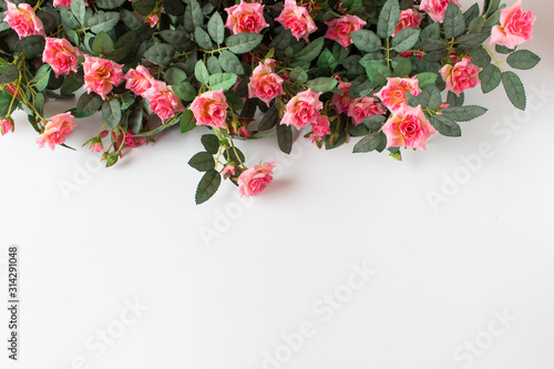 Background with pink artificial roses arranged on top of image. Photo with copy blank space.