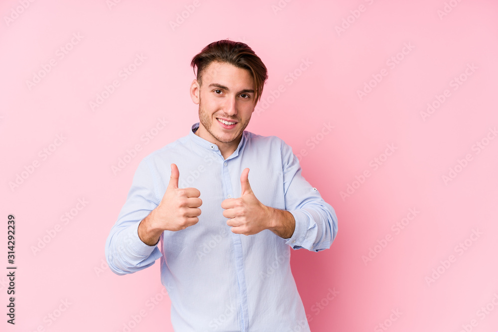Young caucasian man posing in a pink background isolated raising both thumbs up, smiling and confident. Young caucasian man posing in a pink background isolated raising both thumbs up, smiling and confident.