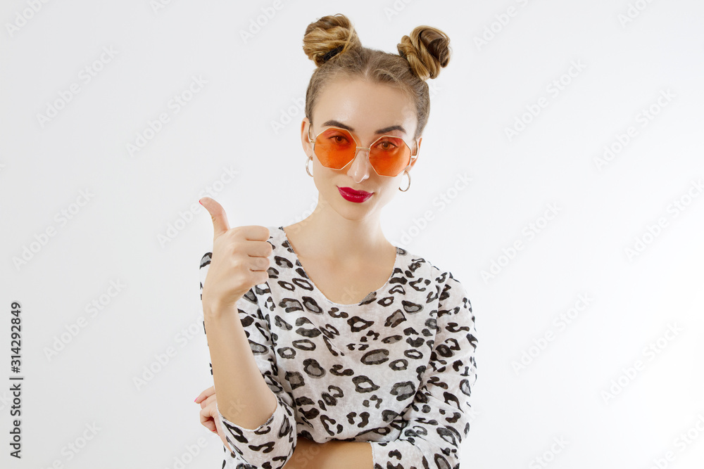 Close-up woman face. Fashion female closeup in trendy clothes isolated on white background. Summer fun time and summertime accessories. Funny girl. Big thumb up. Selective focus