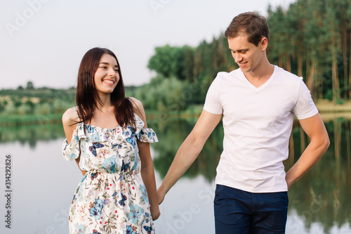 Young loving couple dancing near lake.