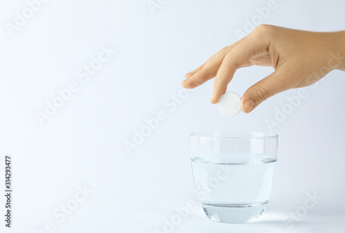 Woman putting tablet into glass of water on white background, space for text