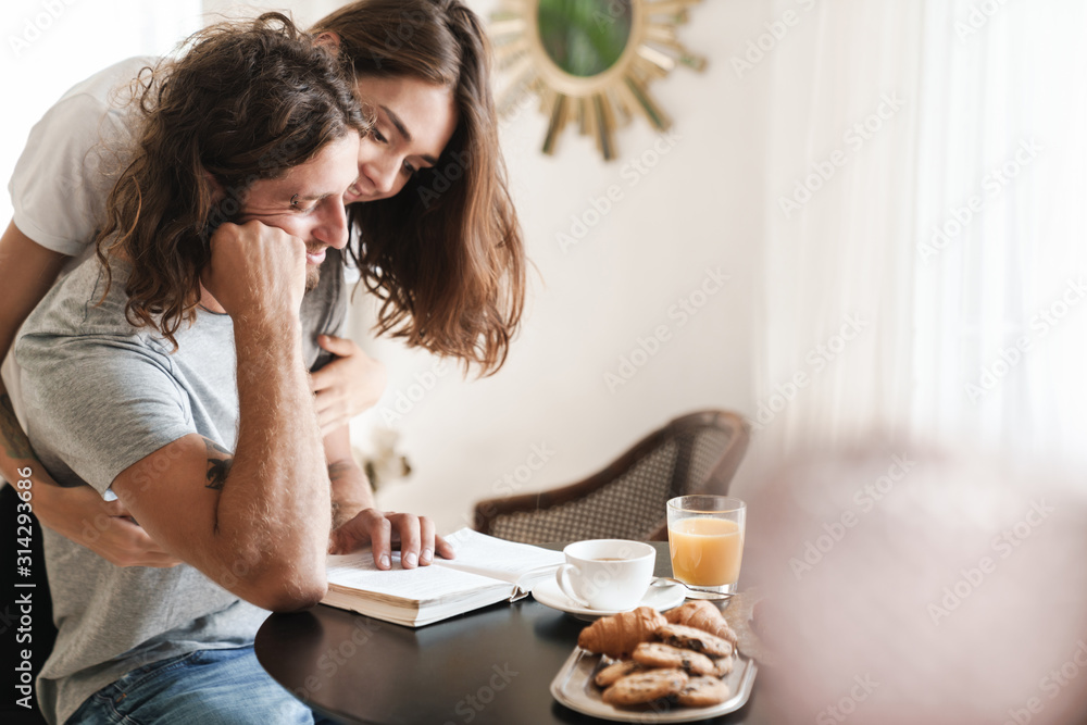 Loving couple indoors at home in kitchen have a breakfast Loving couple indoors at home in kitchen have a breakfast