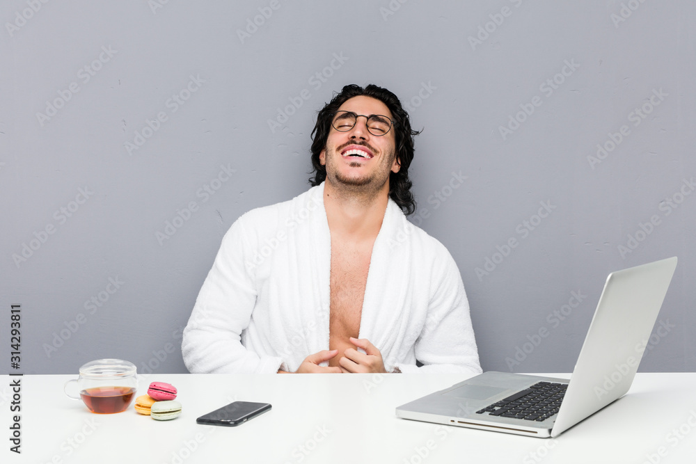 Young handsome man working after a shower laughs and closes eyes, feels relaxed and happy. Young handsome man working after a shower laughs and closes eyes, feels relaxed and happy.