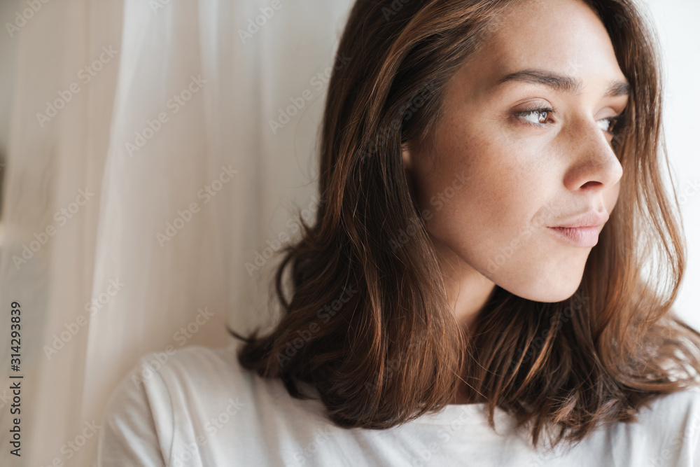 Woman indoors at home posing near window. Woman indoors at home posing near window.