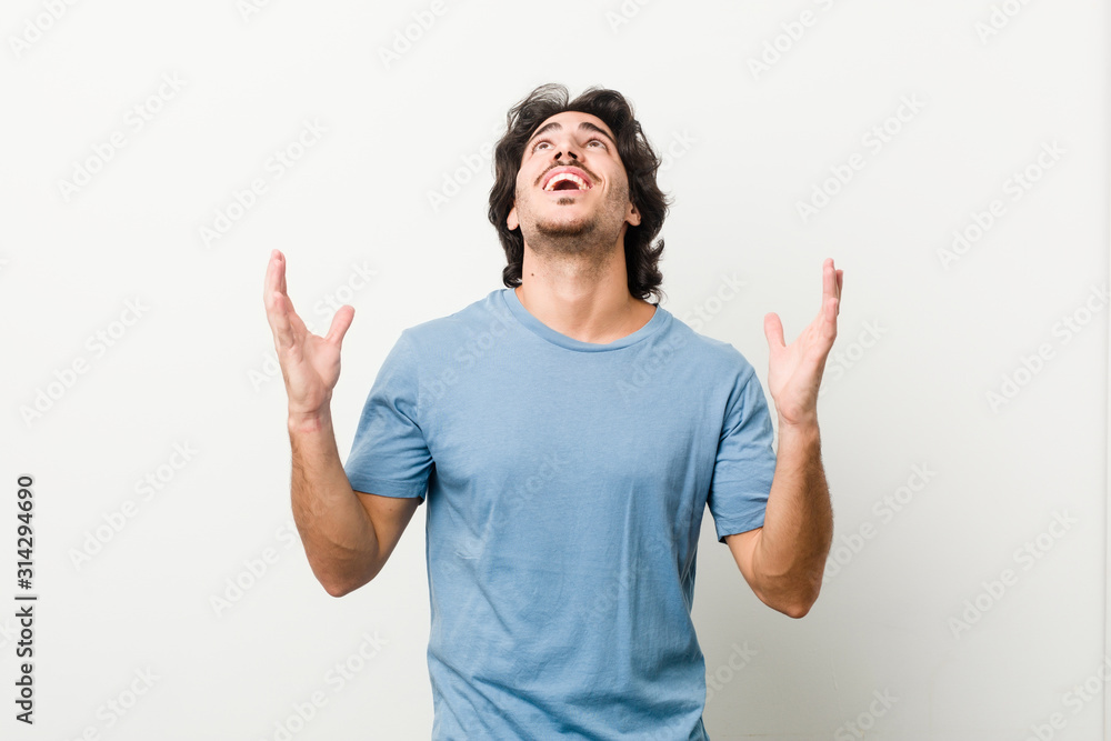 Young handsome man against a white background screaming to the sky, looking up, frustrated.