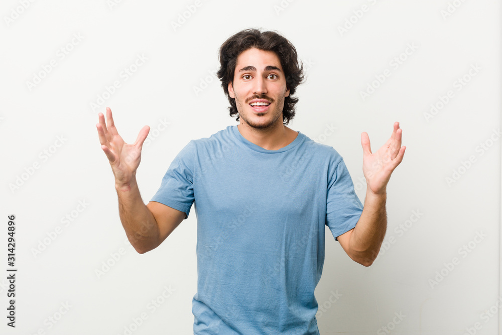 Young handsome man against a white background receiving a pleasant surprise, excited and raising hands. Young handsome man against a white background receiving a pleasant surprise, excited and raising hands.
