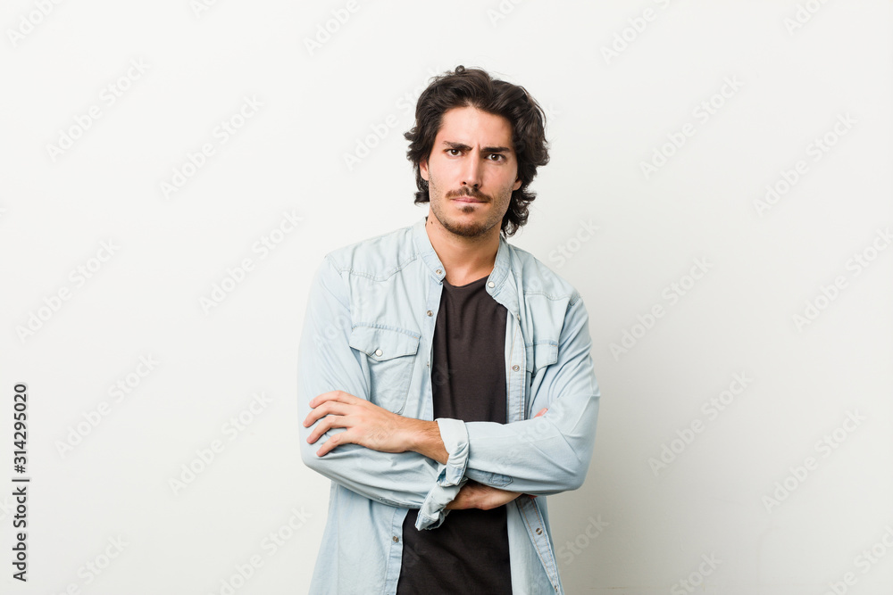 Young handsome man against a white background frowning face in displeasure, keeps arms folded. Young handsome man against a white background frowning face in displeasure, keeps arms folded.