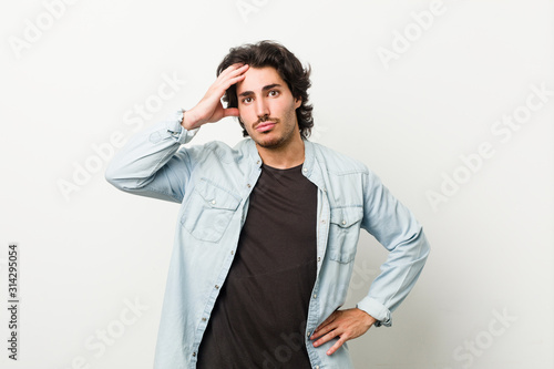Young handsome man against a white background being shocked, she has remembered important meeting.