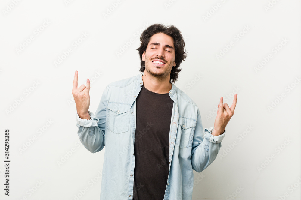 Young handsome man against a white background showing rock gesture with fingers