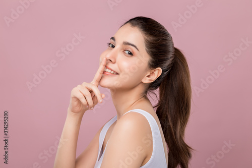 Fotografia Young beautiful Caucasian woman with smiley face touching her nose, surgery nose job concept, isolated on pink