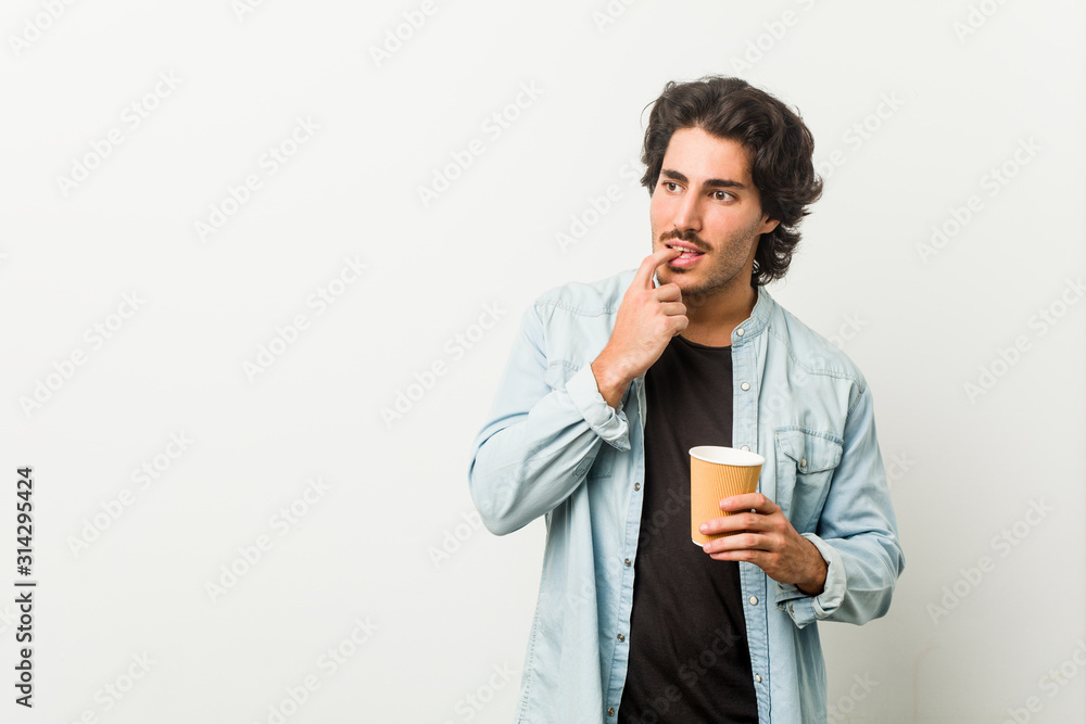 Young cool man drinking a coffee relaxed thinking about something looking at a copy space. Young cool man drinking a coffee relaxed thinking about something looking at a copy space.