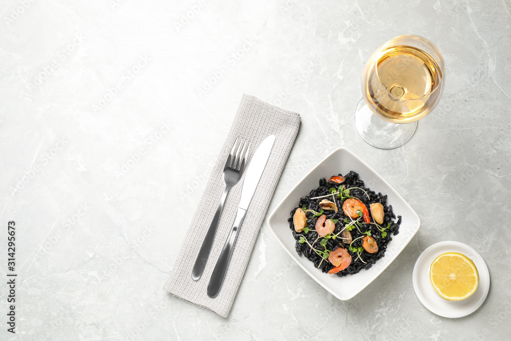 Delicious black risotto with seafood served on light grey marble table. Space for text Delicious black risotto with seafood served on light grey marble table. Space for text