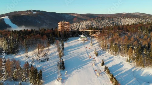 Wooden Observatory Tower in Slotwiny near Krynica in Polend at Winter. 4K Aerial Footage Flying Bacwards. photo