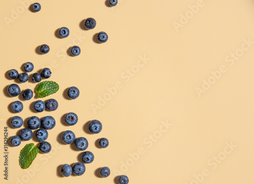 pattern of fresh blueberries and mint leaves is laid out on a yellow background