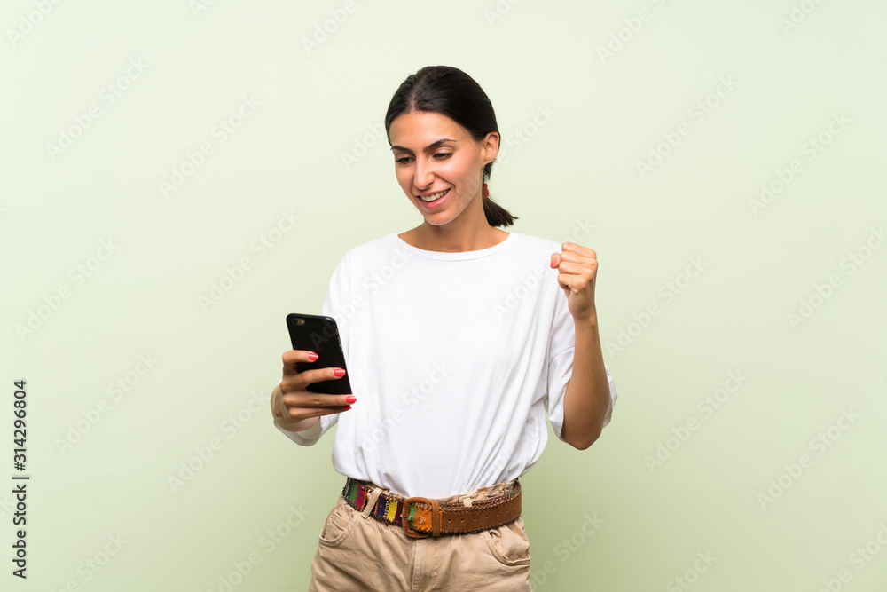 Young woman over isolated green background using mobile phone Young woman over isolated green background using mobile phone