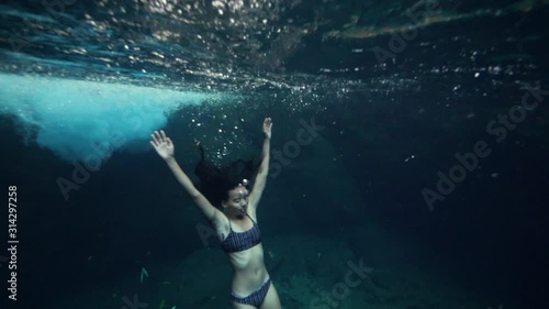 A young skinny woman in bikini floating underwater and holding her breath. photo