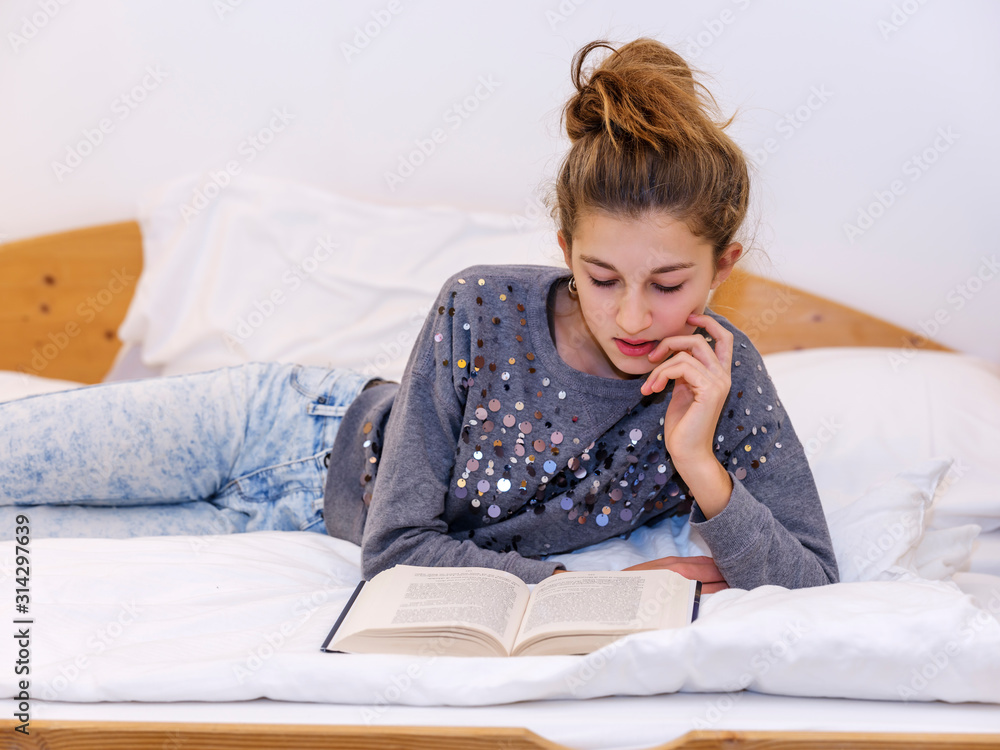 Girl reading a book lying on the bed Girl reading a book lying on the bed