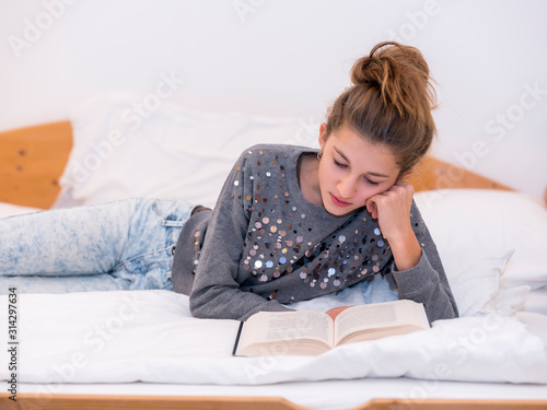 Girl reading a book lying on the bed © trattieritratti