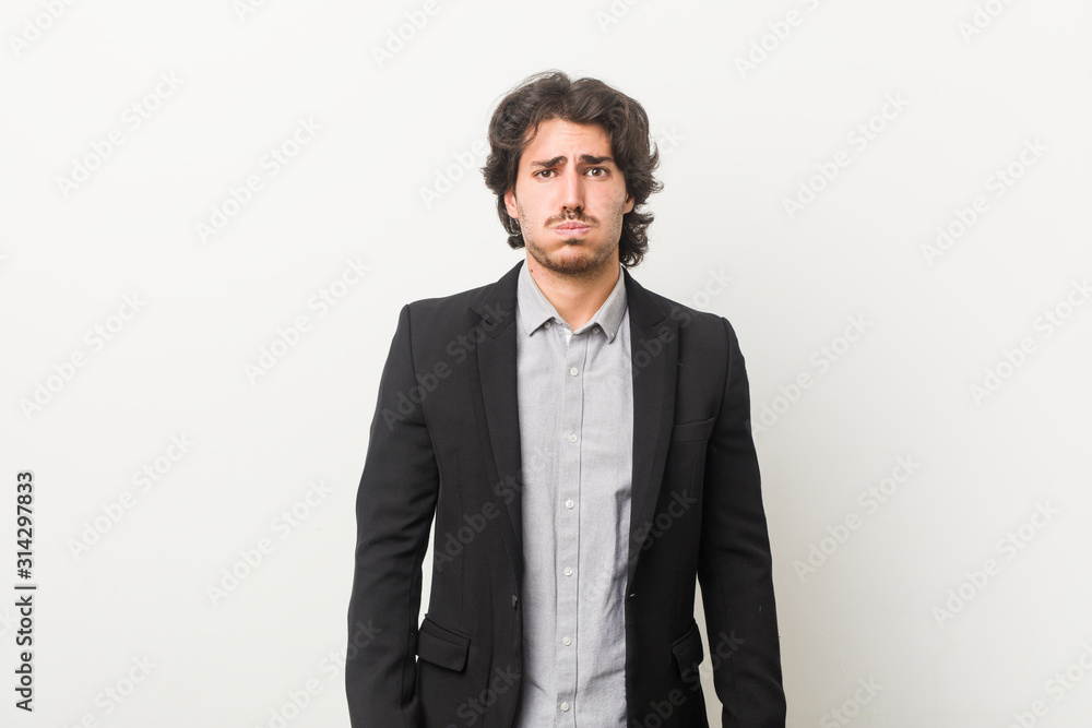 Young business man against a white background blows cheeks, has tired expression. Facial expression concept. Young business man against a white background blows cheeks, has tired expression. Facial expression concept.