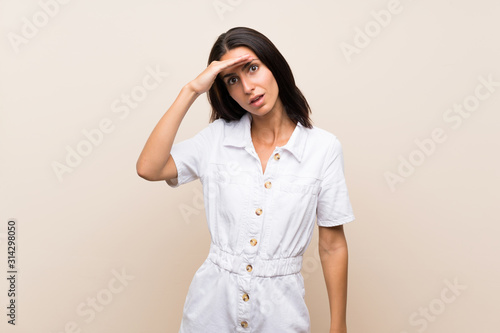 Young woman over isolated background looking far away with hand to look something