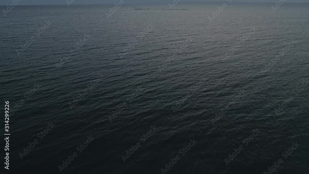 Aerial video of endless, blue, empty sea or ocean water surface at sunset. Pedestal shot, drone camera ascends slowly above water. Aerial video of endless, blue, empty sea or ocean water surface at sunset. Pedestal shot, drone camera ascends slowly above water.