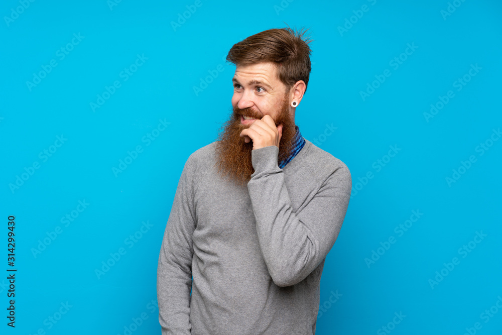 Redhead man with long beard over isolated blue background looking to the side Redhead man with long beard over isolated blue background looking to the side