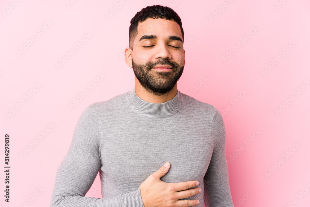 Young latin man against a pink background isolated touches tummy, smiles gently, eating and satisfaction concept. Young latin man against a pink background isolated touches tummy, smiles gently, eating and satisfaction concept.