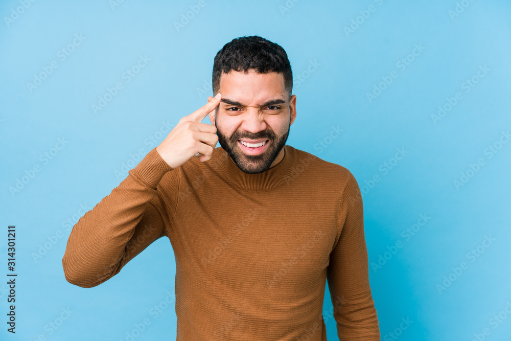Young latin man against a blue  background isolated showing a disappointment gesture with forefinger.