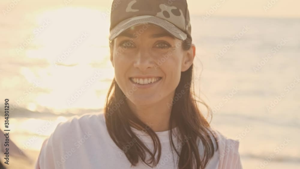 Smiling young woman volunteer is cleaning beach from garbage with group of people volunteers Smiling young woman volunteer is cleaning beach from garbage with group of people volunteers