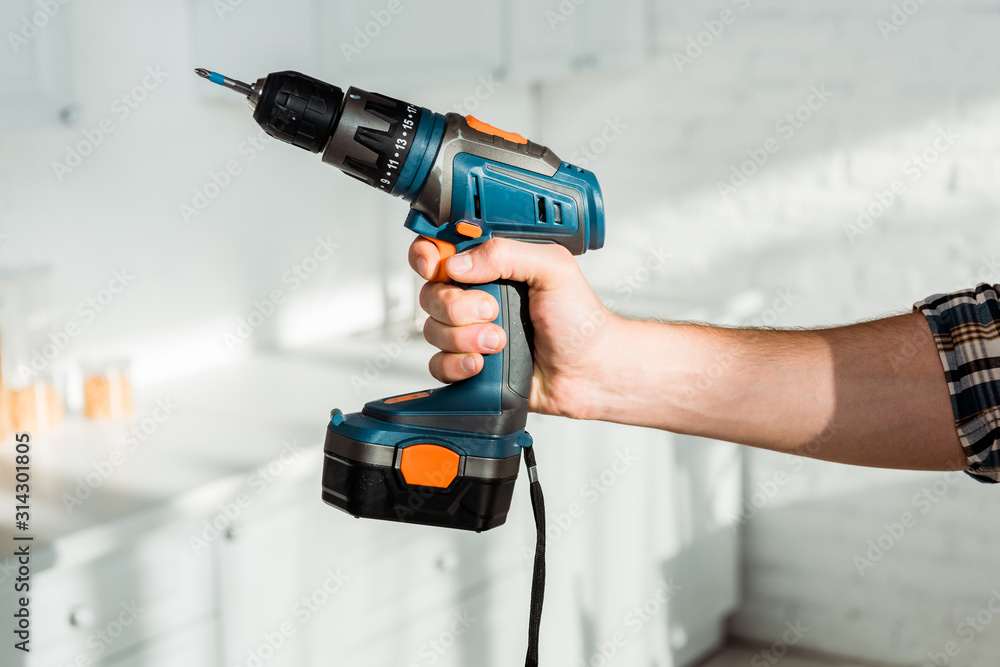 cropped view of installer holding hammer drill in hand