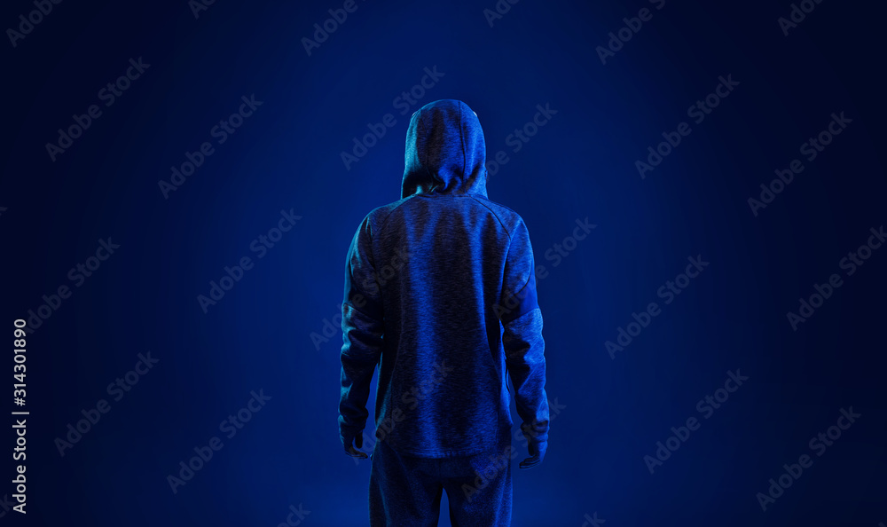 Back view of hacker in hoodie. Dangerous hooded hacker. Internet, cyber crime, cyber attack, system breaking and malware concept. Anonymous. Dark background. Back view of hacker in hoodie. Dangerous hooded hacker. Internet, cyber crime, cyber attack, system breaking and malware concept. Anonymous. Dark background.