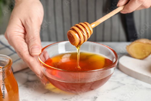 Woman with tasty honey at marble table, closeup