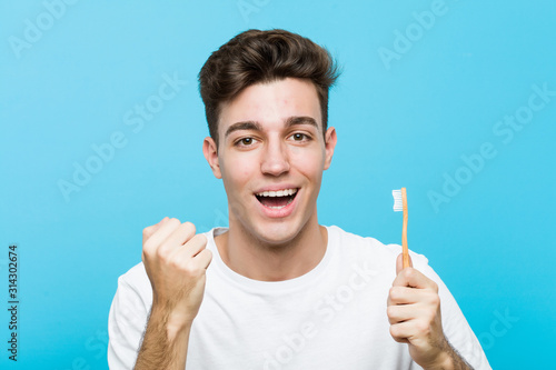 Young caucasian man holding a toothbrush Young indian woman wearing a pajamas and sleep mask isolated holding a pillow cheering carefree and excited. Victory concept.< mixto >