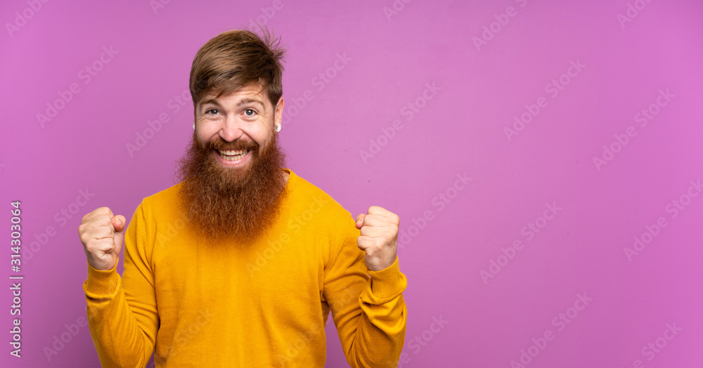 Redhead man with long beard over isolated purple background celebrating a victory in winner position Redhead man with long beard over isolated purple background celebrating a victory in winner position