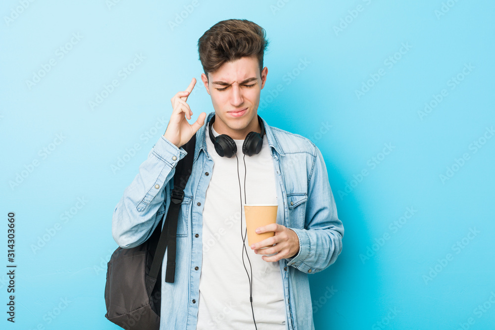 Young caucasian student man holding a take away coffee crossing fingers for having luck Young caucasian student man holding a take away coffee crossing fingers for having luck