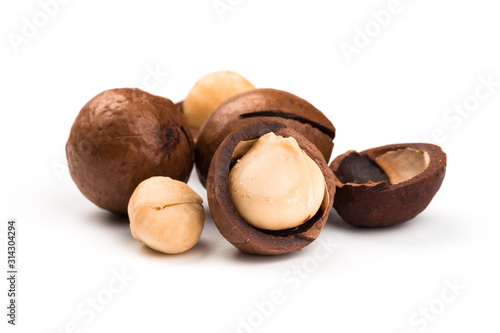 Raw not peeled whole macadamia nuts with shelled kernels isolated on white. Macro view. Healthy food. Protein source.