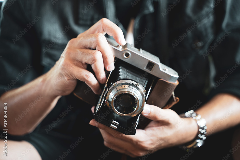 a man holding the vintage old film camera   - obrazy, fototapety, plakaty 