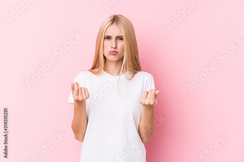 Young blonde woman on pink background showing that she has no money.