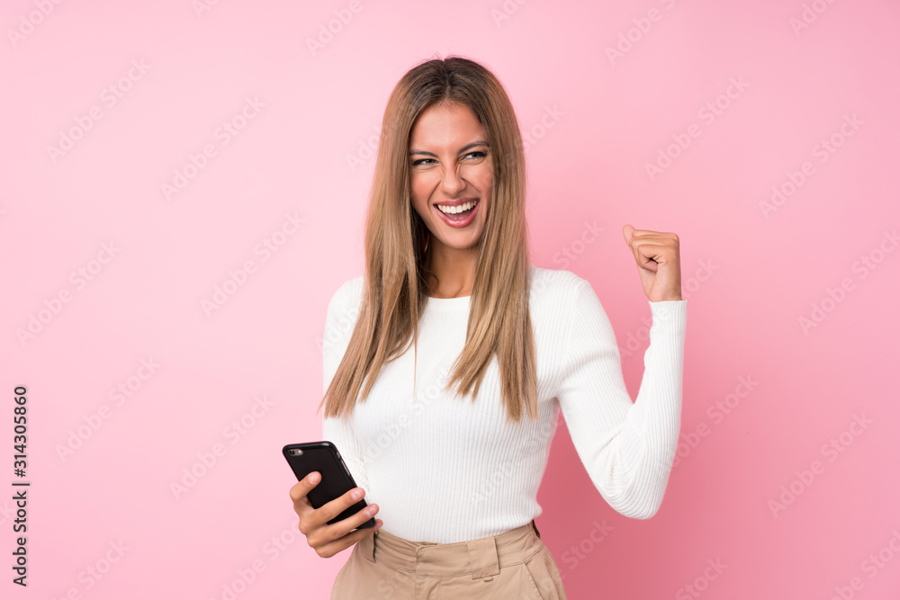 Young blonde woman over isolated pink background using mobile phone Young blonde woman over isolated pink background using mobile phone
