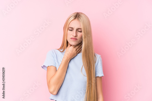 Young blonde woman on pink background suffers pain in throat due a virus or infection.
