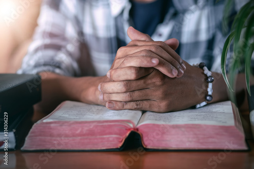 Hands of an unrecognizable man with Bible praying, Christian concept.
