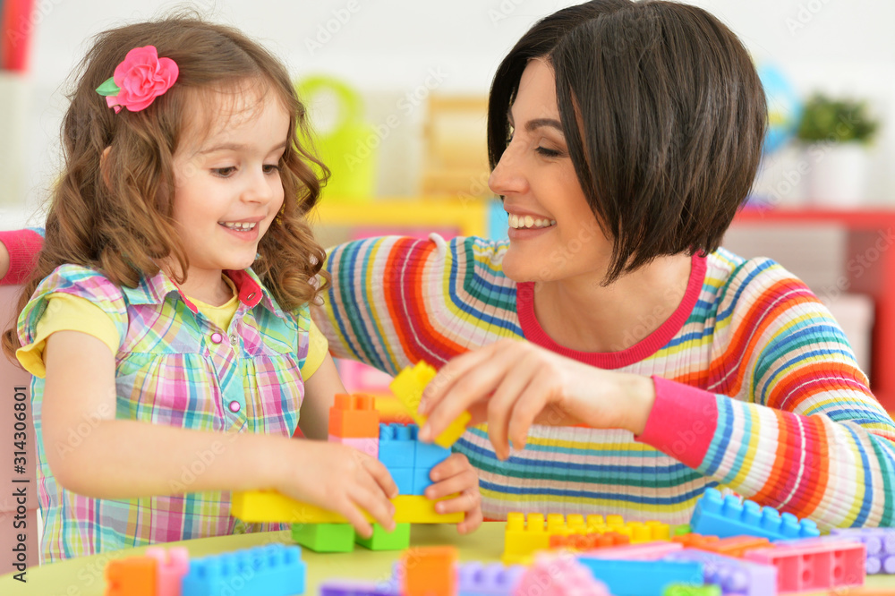 Fototapeta premium Portrait of young mother playing with little daughter