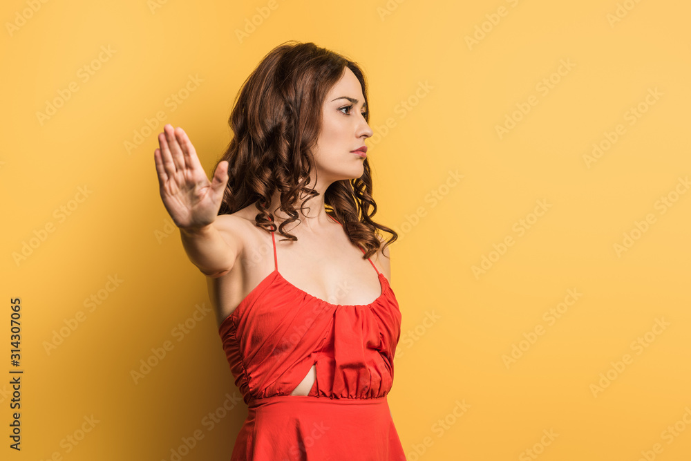 displeased girl showing stop gesture on yellow background displeased girl showing stop gesture on yellow background